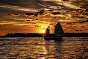 A sail boat crossing the path of the setting sun at Key West, Florida.